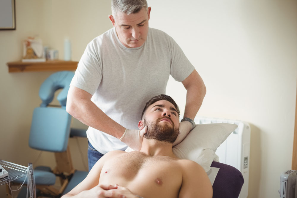 Physiotherapist examining neck of a patient in clinic